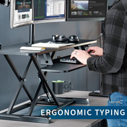 Spacious height adjustable desk riser with articulating triple monitor mount.