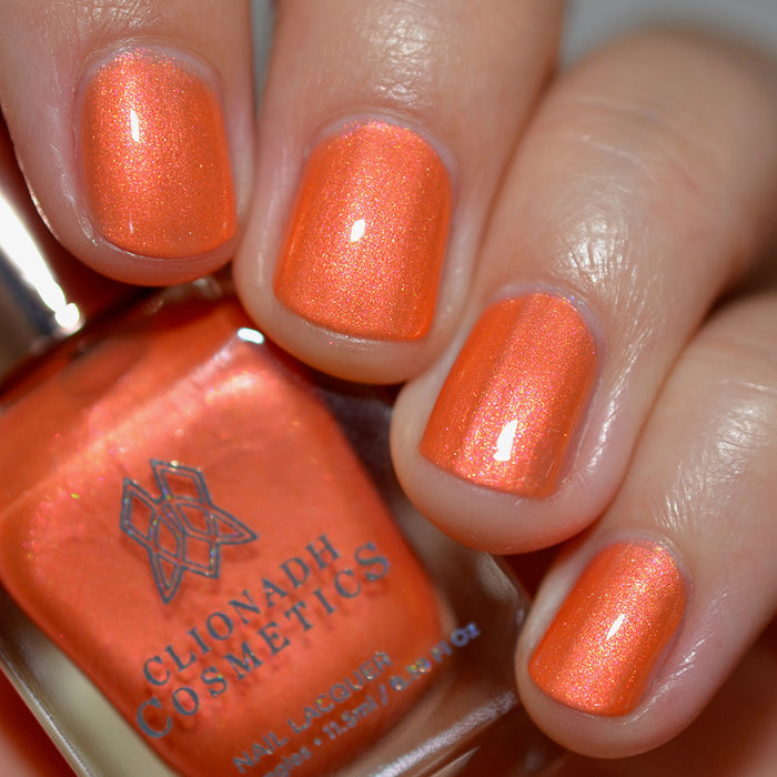 Close-up of nails painted with Fall Festival Nail Lacquer on fair skin tone. Hand is holding polish bottle.