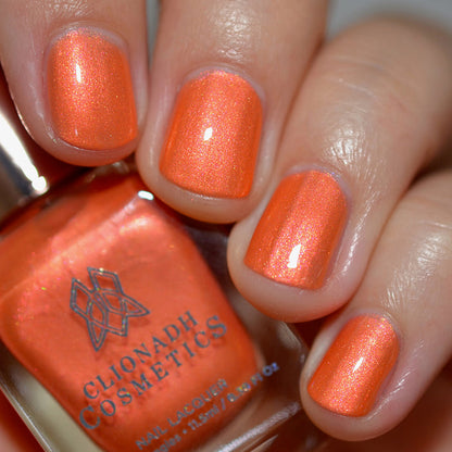 Close-up of nails painted with Fall Festival Nail Lacquer on fair skin tone. Hand is holding polish bottle.