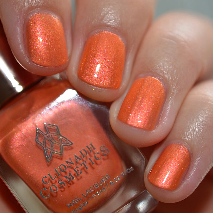 Close-up of nails painted with Fall Festival Nail Lacquer on fair skin tone. Hand is holding polish bottle.