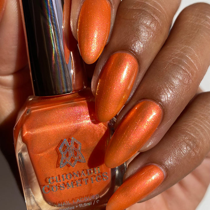 Close-up of nails painted with Fall Festival Nail Lacquer on medium skin tone. Hand is holding polish bottle.