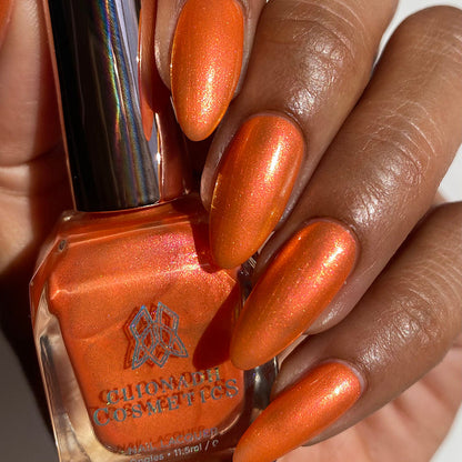 Close-up of nails painted with Fall Festival Nail Lacquer on medium skin tone. Hand is holding polish bottle.
