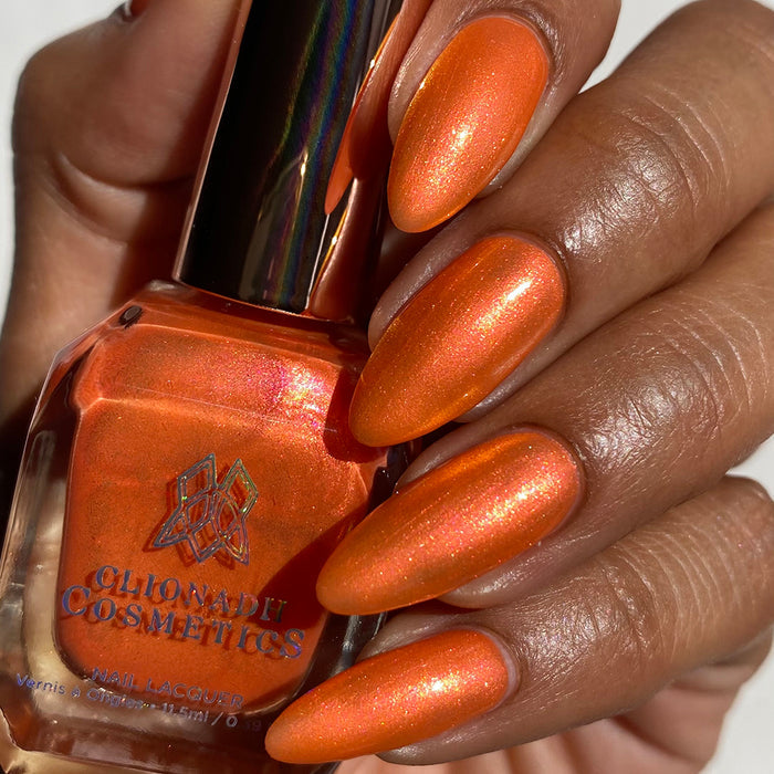 Close-up of nails painted with Fall Festival Nail Lacquer on medium skin tone. Hand is holding polish bottle.