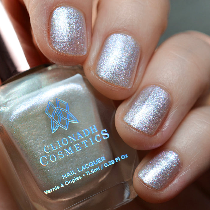 Close-up of nails painted with Spirit Nail Lacquer on fair skin tone. Hand is holding polish bottle.