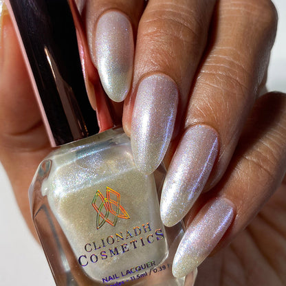 Close-up of nails painted with Spirit Nail Lacquer on medium skin tone. Hand is holding polish bottle.