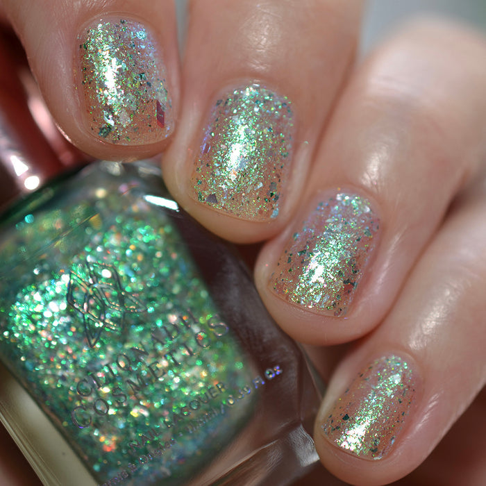 Close-up of nails painted with Fauxjito Nail Lacquer on fair skin tone. Hand is holding polish bottle.