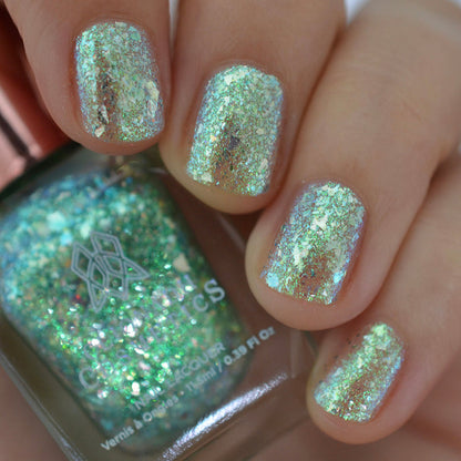 Close-up of nails painted with Fauxjito Nail Lacquer on fair skin tone. Hand is holding polish bottle.