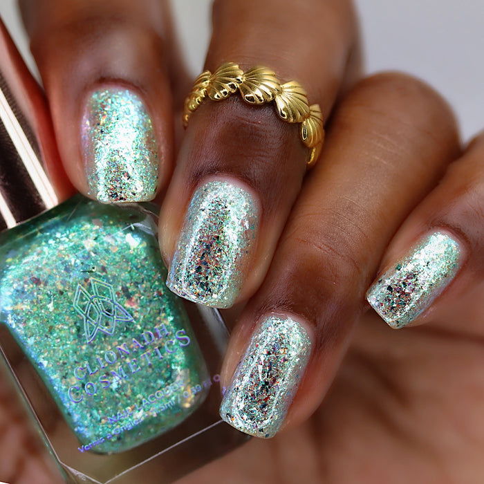 Close-up of nails painted with Fauxjito Nail Lacquer on deep skin tone. Hand is holding polish bottle.