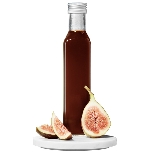 A bottle of Fig Balsamic Vinegar with a fig and slices of fresh fig placed in front of the bottle.