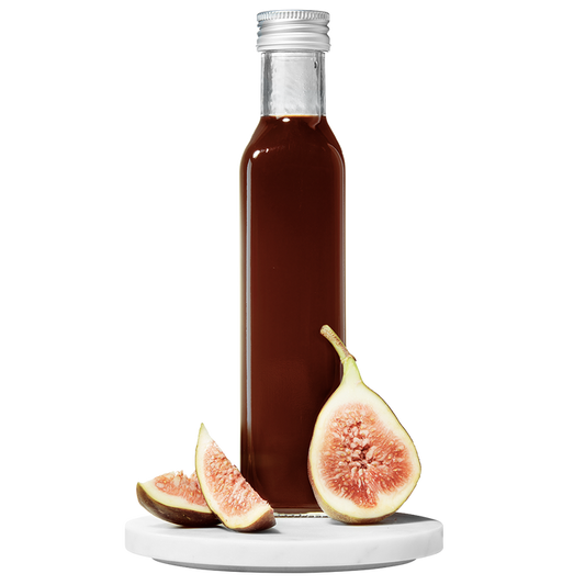 A bottle of Fig Balsamic Vinegar with a fig and slices of fresh fig placed in front of the bottle.