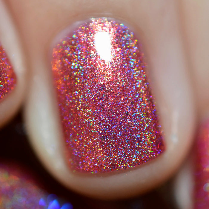 Close-up of one nail painted with Flamin' Hot Holo Nail Lacquer on fair skin tone.