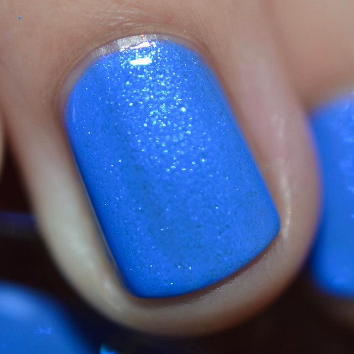 Close-up of one nail painted with Frigid Nail Lacquer on fair skin tone. Emphasizes glitter particles.
