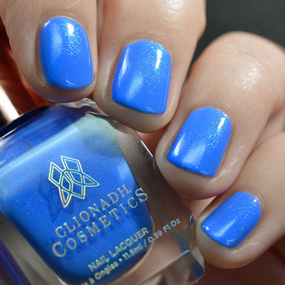 Close-up of nails painted with Frigid Nail Lacquer on fair skin tone. Hand is holding polish bottle.