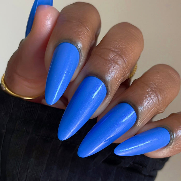 Close-up of nails painted with Frigid Nail Lacquer on deep skin tone, on a beige background.