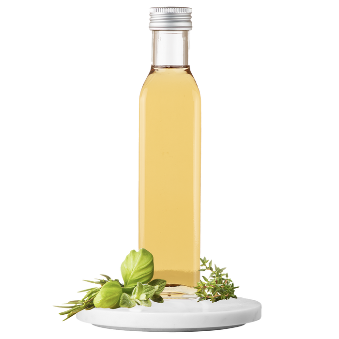 A bottle of Garden Herb Vinegar with a white label and a small green herb sprig on top, set against a transparent background.