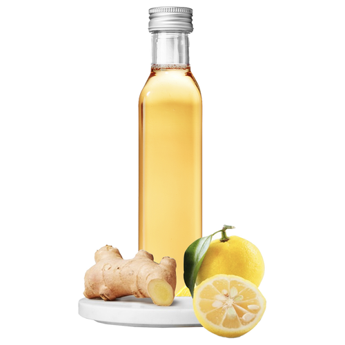 A clear bottle of Ginger Yuzu Vinegar with a lemon and ginger root in the foreground.