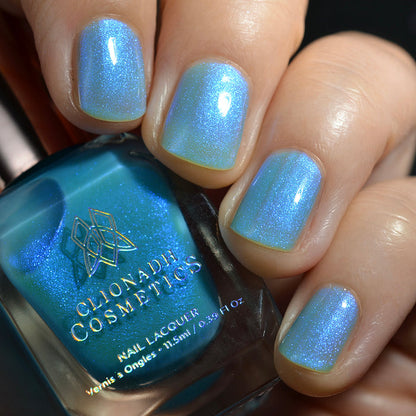 Close-up of nails painted with Ginto Nail Lacquer on fair skin tone. Hand is holding polish bottle.