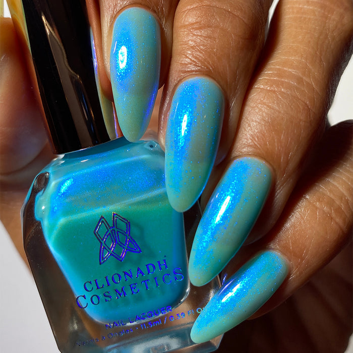 Close-up of nails painted with Ginto Nail Lacquer on medium skin tone. Hand is holding polish bottle.
