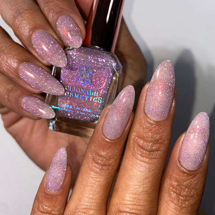 Nails painted with God Speed Nail Lacquer on medium skin tone. Hand is holding polish bottle.