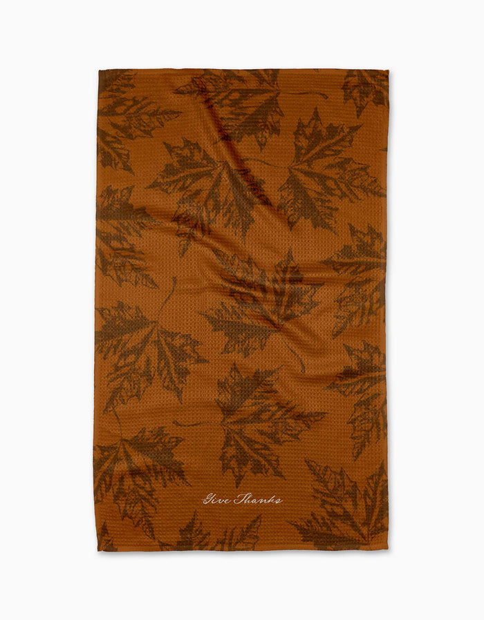 Brown towel with leaf pattern and 'Give Thanks' text on a white background