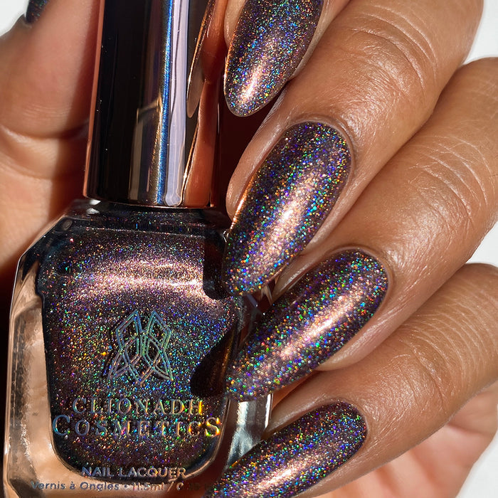 Close-up of nails painted with Graveyard Nail Lacquer on medium skin tone. Hand is holding polish bottle.