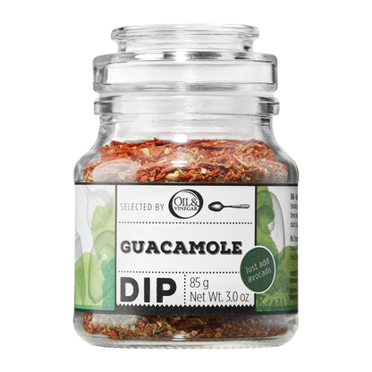 A glass jar containing Guacamole Dip with visible herb mix. The label shows the product name and weight.