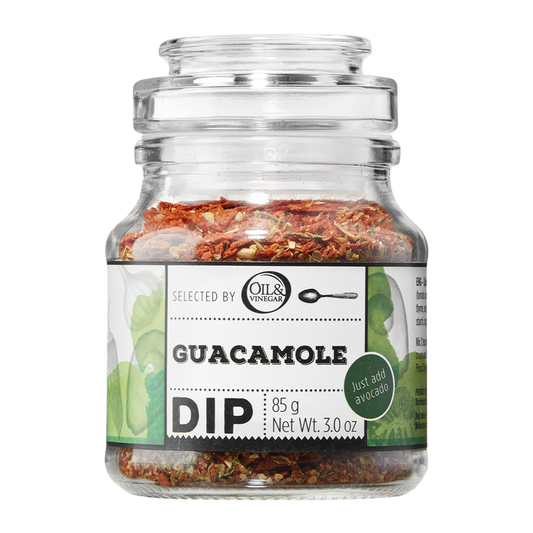 A glass jar containing Guacamole Dip with visible herb mix. The label shows the product name and weight.