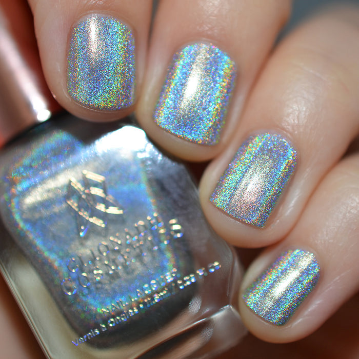 Close-up of nails painted with H₂Olo Nail Lacquer on fair skin tone. Hand is holding polish bottle.