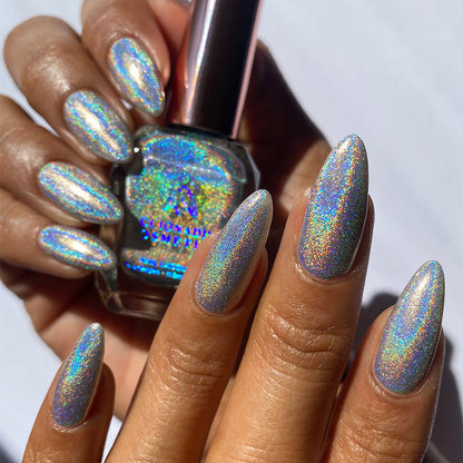 Close-up of nails painted with H₂Olo Nail Lacquer on medium skin tone. Hand is holding polish bottle.