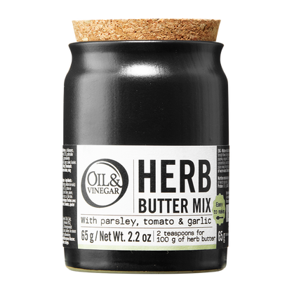 A jar of Herb Butter Mix by Oil & Vinegar with labels indicating the mix contains parsley, tomato, and garlic. The jar is sealed with a cork stopper.