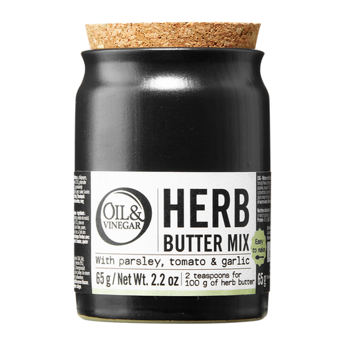 A jar of Herb Butter Mix by Oil & Vinegar with labels indicating the mix contains parsley, tomato, and garlic. The jar is sealed with a cork stopper.