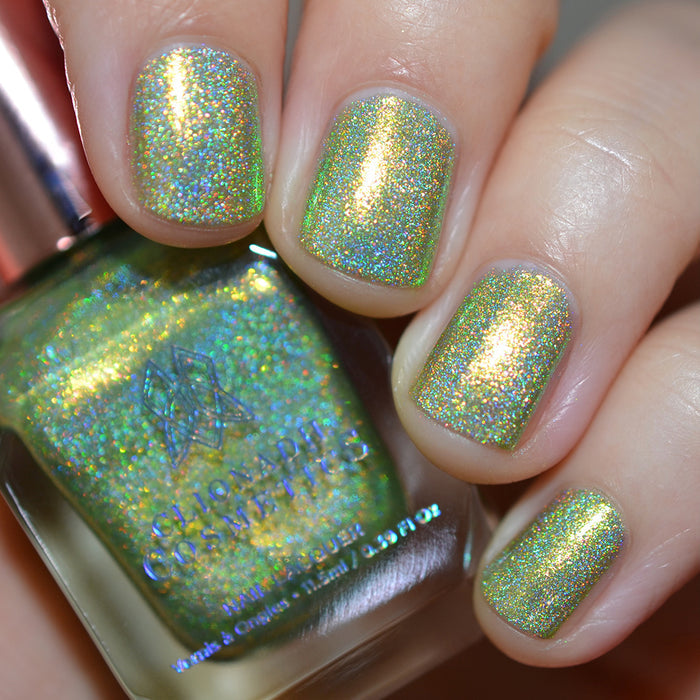 Close-up of nails painted with Holondaise Nail Lacquer on fair skin tone. Hand is holding polish bottle.