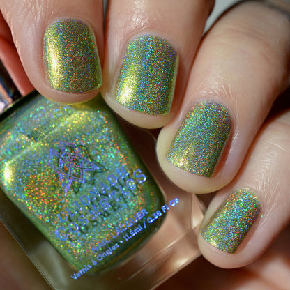Close-up of nails painted with Holondaise Nail Lacquer on fair skin tone. Hand is holding polish bottle.