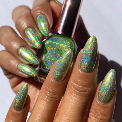Close-up of nails painted with Holondaise Nail Lacquer on medium skin tone. Hand is holding polish bottle.