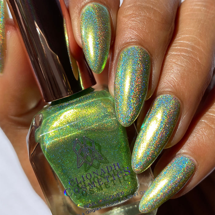 Close-up of nails painted with Holondaise Nail Lacquer on medium skin tone. Hand is holding polish bottle.