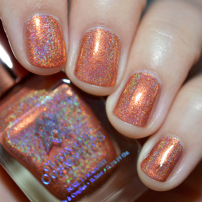 Close-up of nails painted with Holoritos Nail Lacquer on fair skin tone. Hand is holding polish bottle.