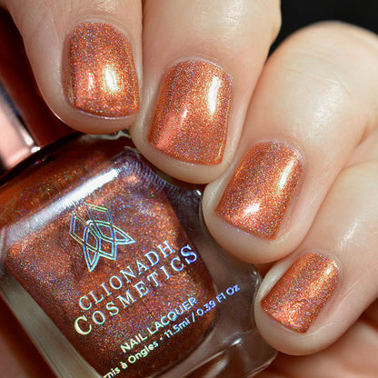 Close-up of nails painted with Holoritos Nail Lacquer on fair skin tone. Hand is holding polish bottle.