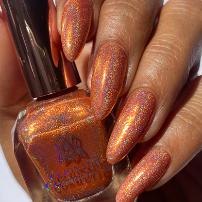 Close-up of nails painted with Holoritos Nail Lacquer on medium skin tone. Hand is holding polish bottle.