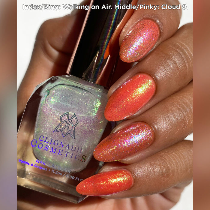 Close-up of nails painted with Walking on Air and Cloud 9 Nail Lacquers over an orange base on medium skin tone.