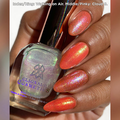 Close-up of nails painted with Walking on Air and Cloud 9 Nail Lacquers over an orange base on medium skin tone.