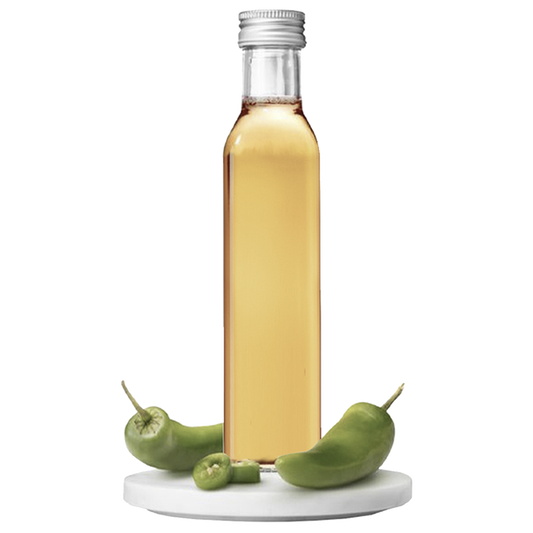 A bottle of Jalapeño Vinegar with whole green jalapeños displayed in front of it.