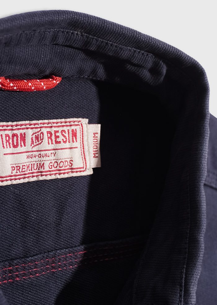Close-up of a navy collar with a red tag reading "Iron and Resin, High Quality, Premium Goods, Medium" in white and red stitching.