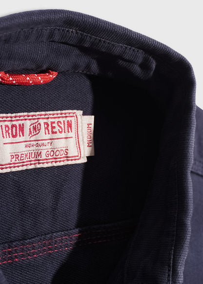 Close-up of a navy collar with a red tag reading "Iron and Resin, High Quality, Premium Goods, Medium" in white and red stitching.