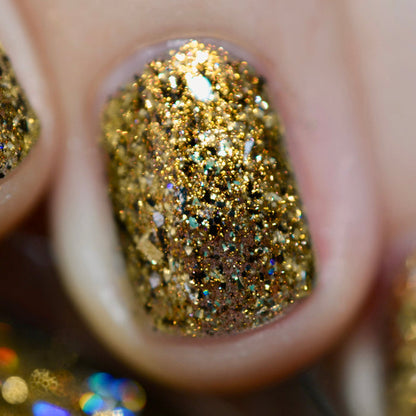 Close-up of one nail painted with Kiss Nail Lacquer on fair skin tone. Emphasizes chunky gold flakes.