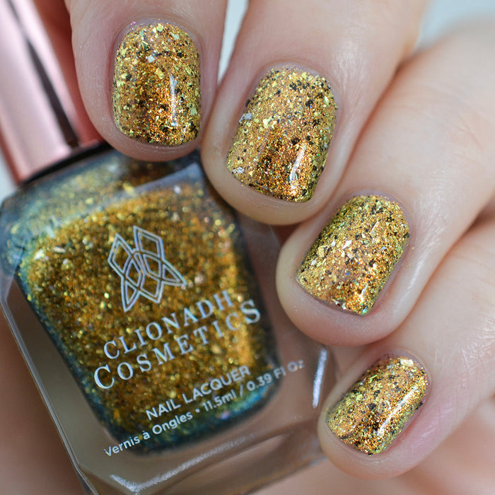Close-up of nails painted with Kiss Nail Lacquer on fair skin tone. Hand is holding polish bottle.