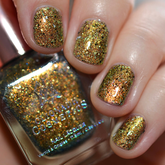 Nails painted with Kiss Nail Lacquer on fair skin tone. Hand is holding polish bottle.