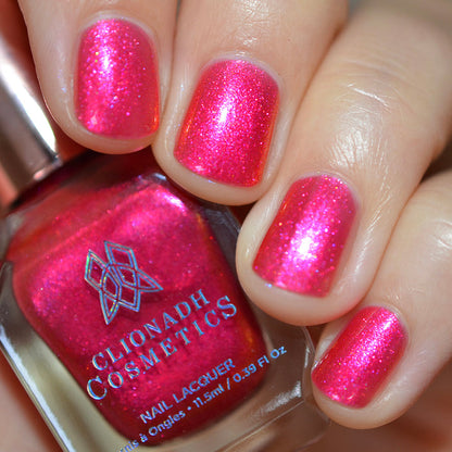 Close-up of nails painted with La Vie En Rose Nail Lacquer on fair skin tone. Hand is holding polish bottle.