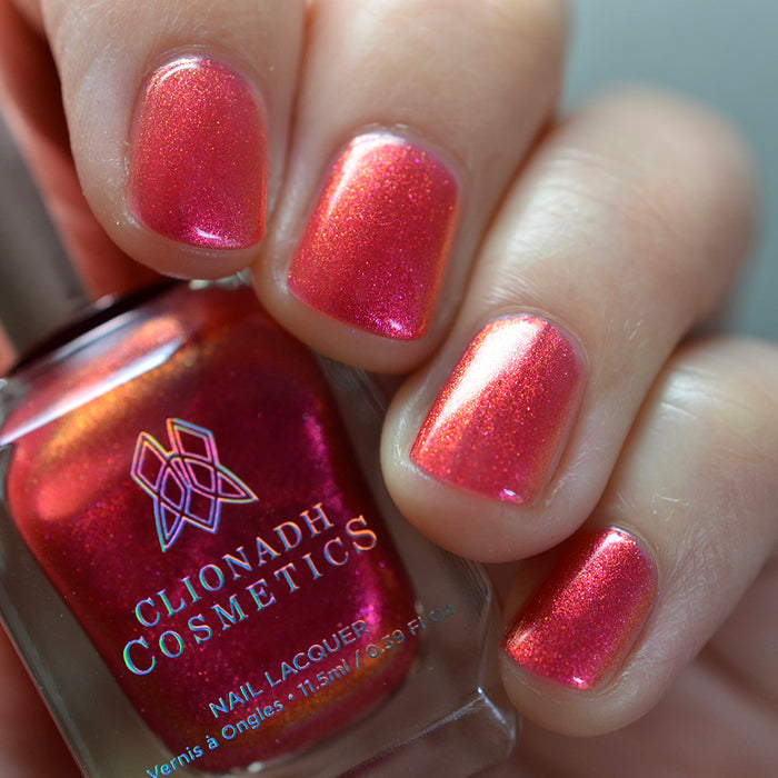 Close-up of nails painted with La Vie En Rose Nail Lacquer on fair skin tone. Hand is holding polish bottle.