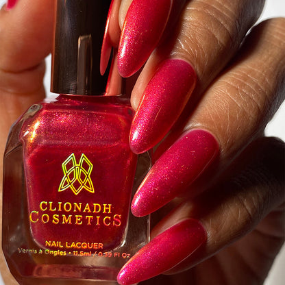 Close-up of nails painted with La Vie En Rose Nail Lacquer on medium skin tone. Hand is holding polish bottle.