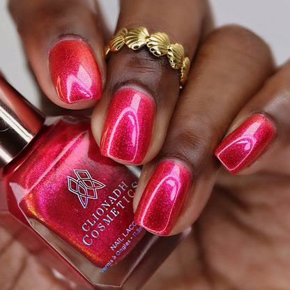 Close-up of nails painted with La Vie En Rose Nail Lacquer on deep skin tone. Hand is holding polish bottle.